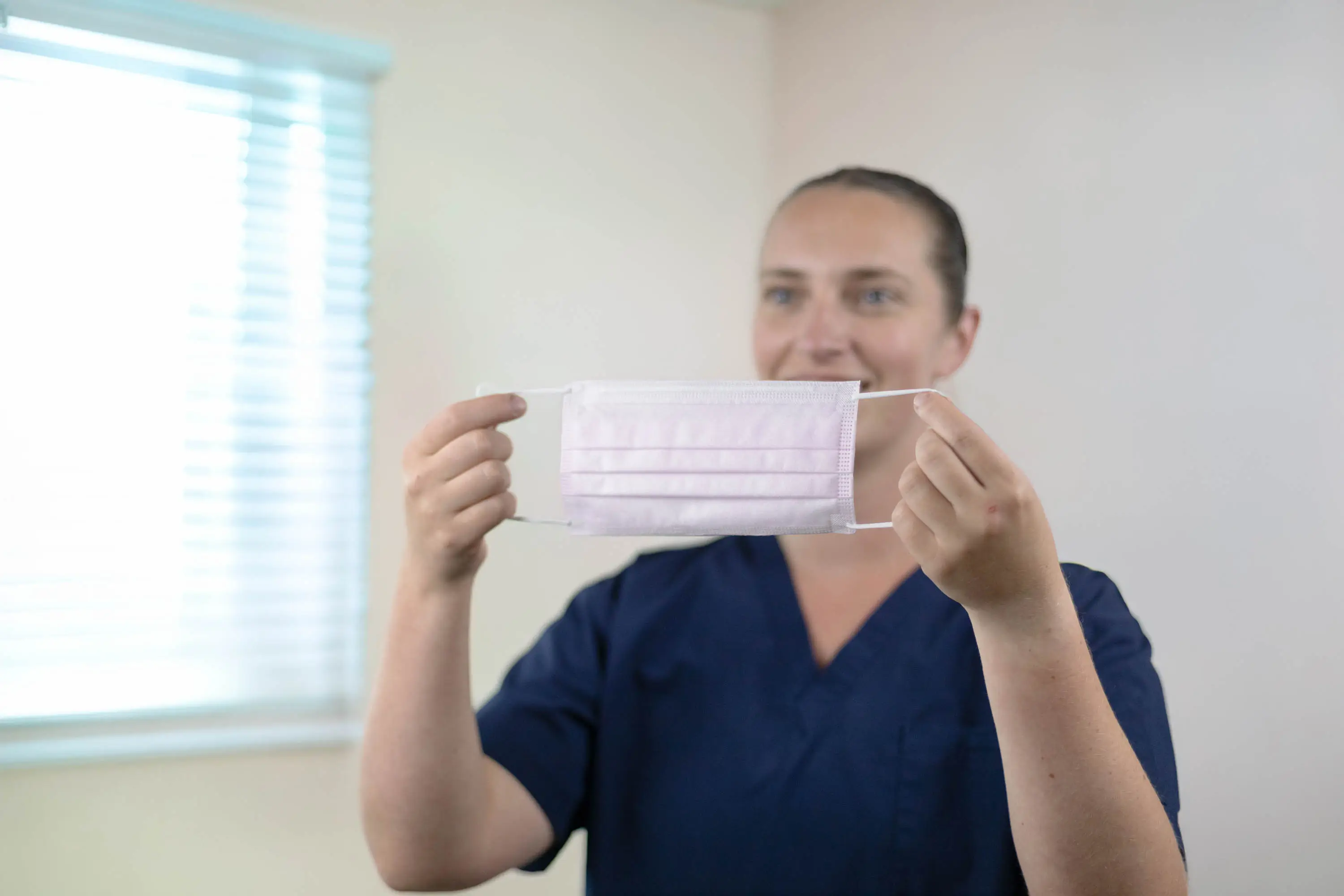 Healthcare worker holding up a pink medical face mask