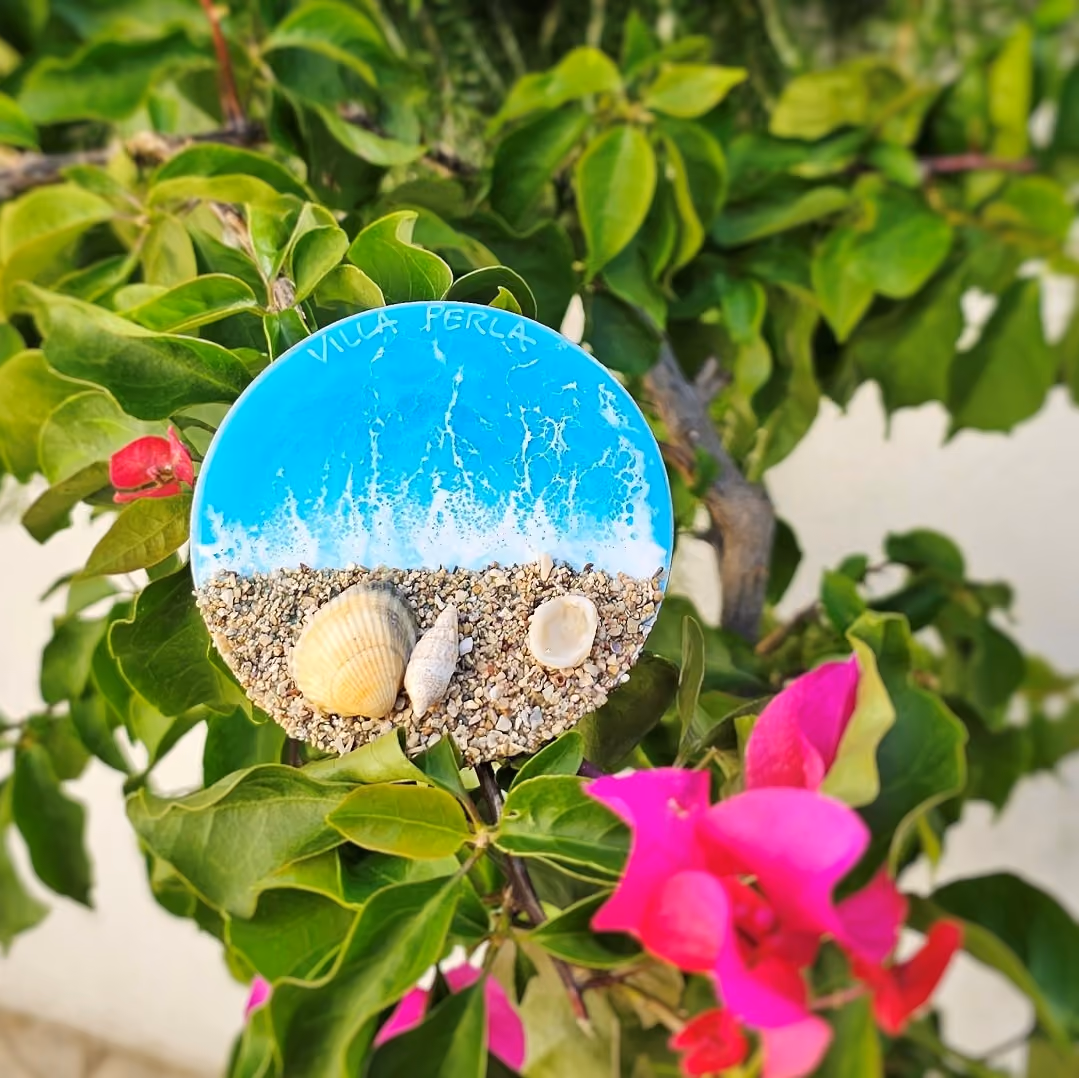 Villa Perla coastal-inspired welcome detail with seashell decoration surrounded by Mediterranean flowers and greenery