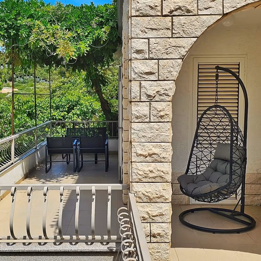 Villa Perla terrace with hanging chair and outdoor seating surrounded by Mediterranean greenery in Okrug Gornji near Trogir