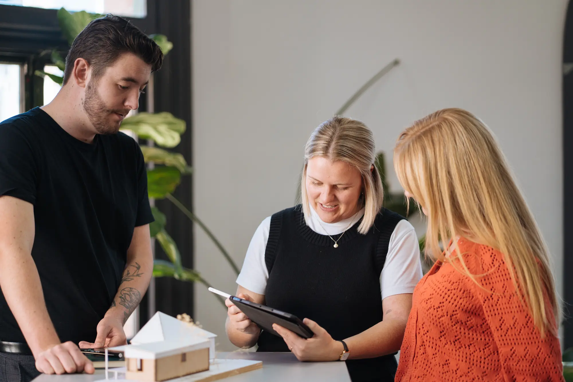 Architect with ipad showing client work with model of building in front