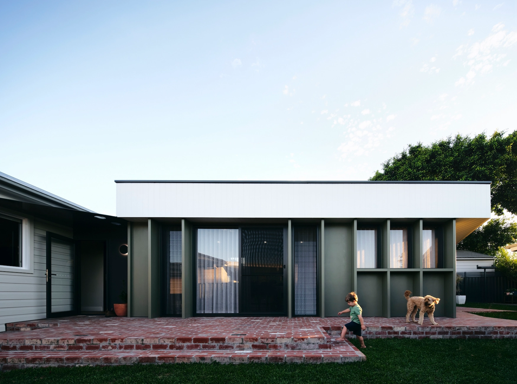 Child with brown dog play on porch in front of modern home