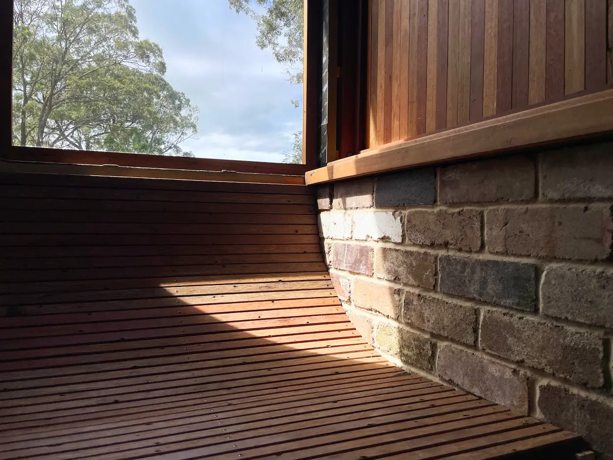 Image of window with curved wooden day bed and brick wall