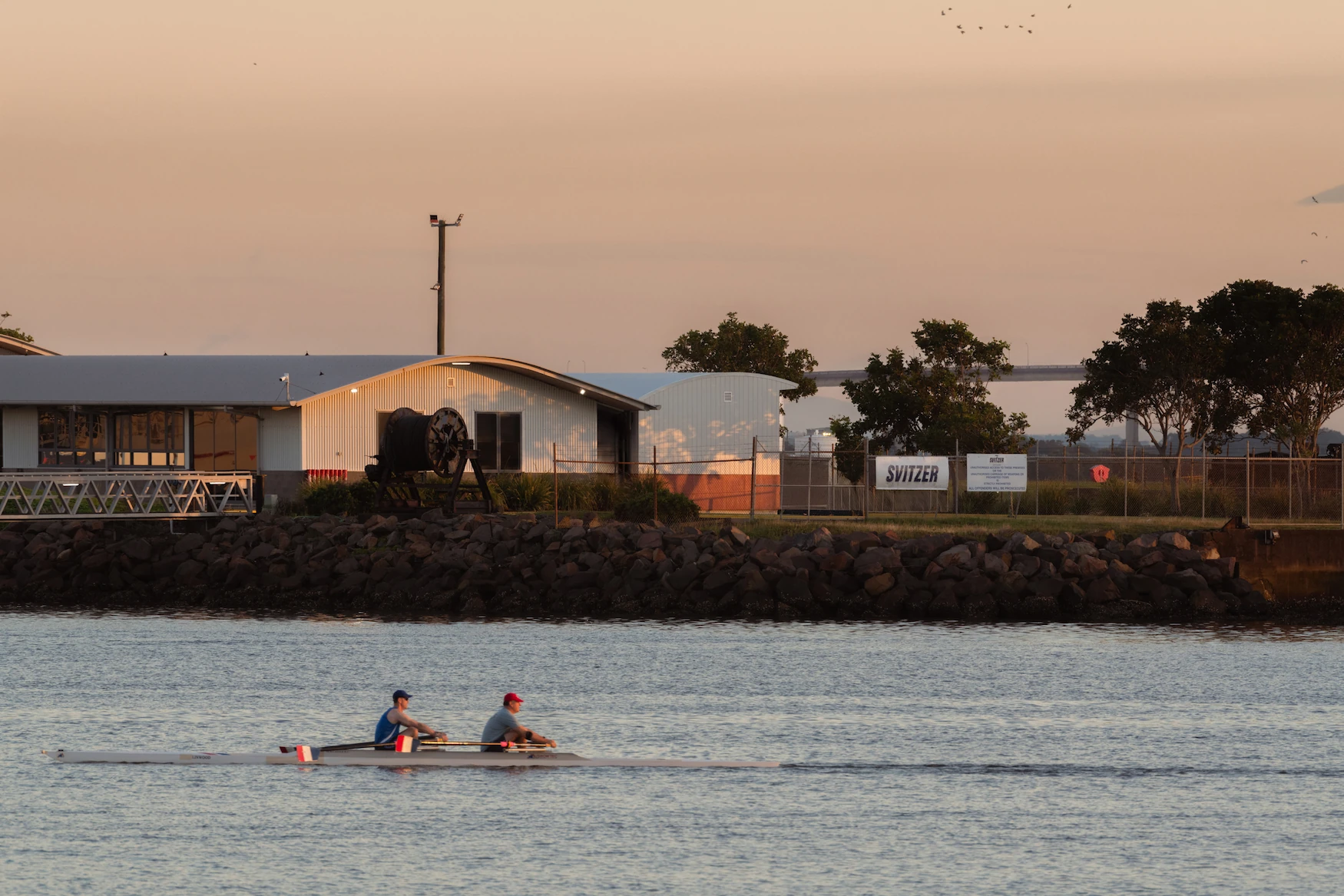 Two people in a canoe in the harbour with a building in the background
