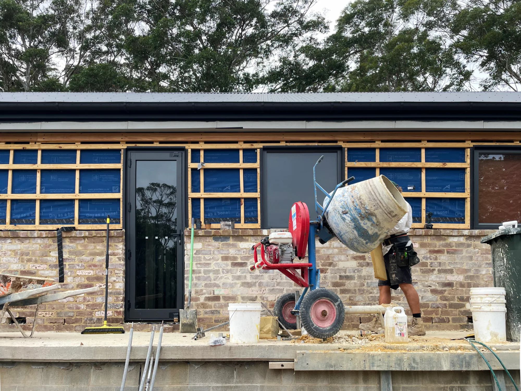 Construction site house with cement mixer, wooden framework and tradesman