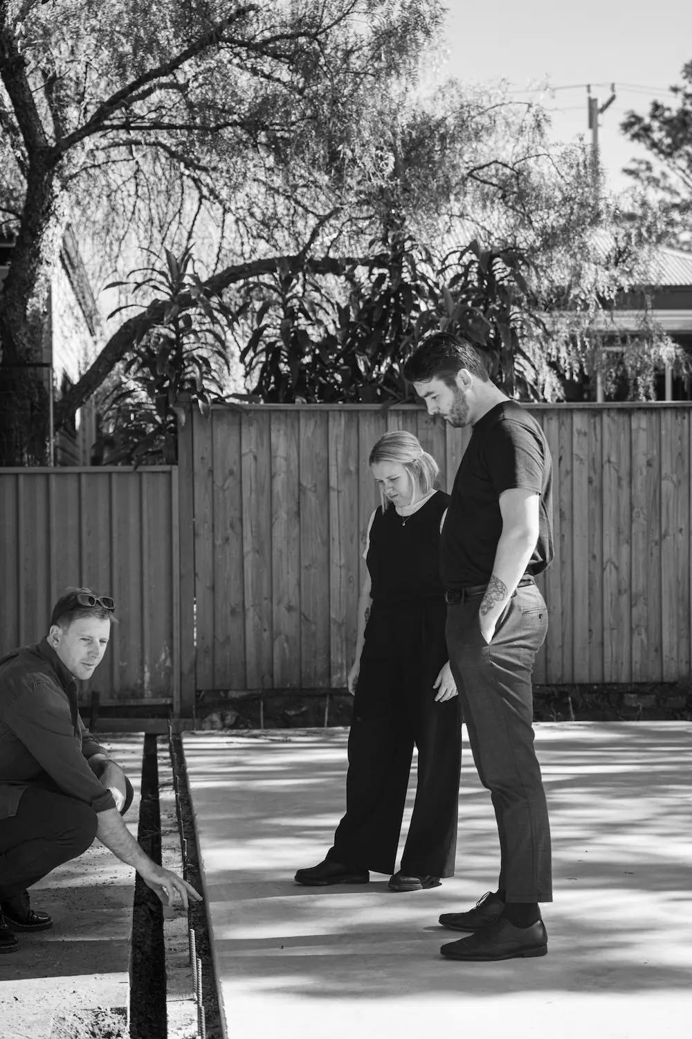 lack and white photo of three people on concrete slab on construction site