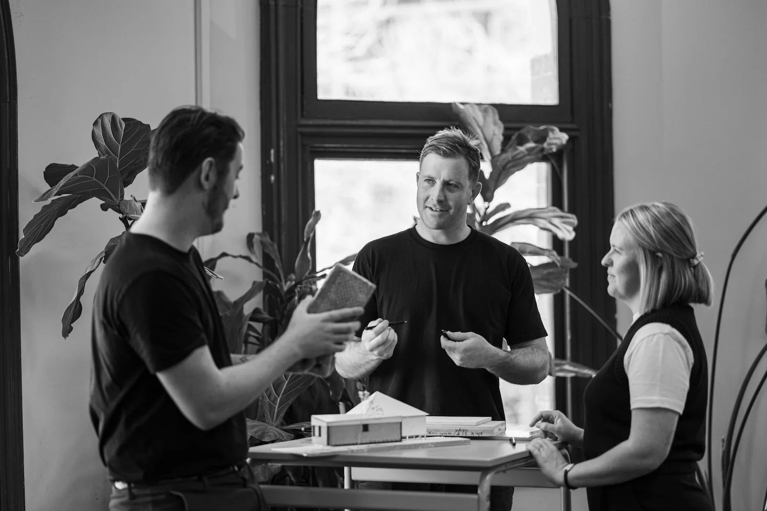Black and white photo of three people with model home