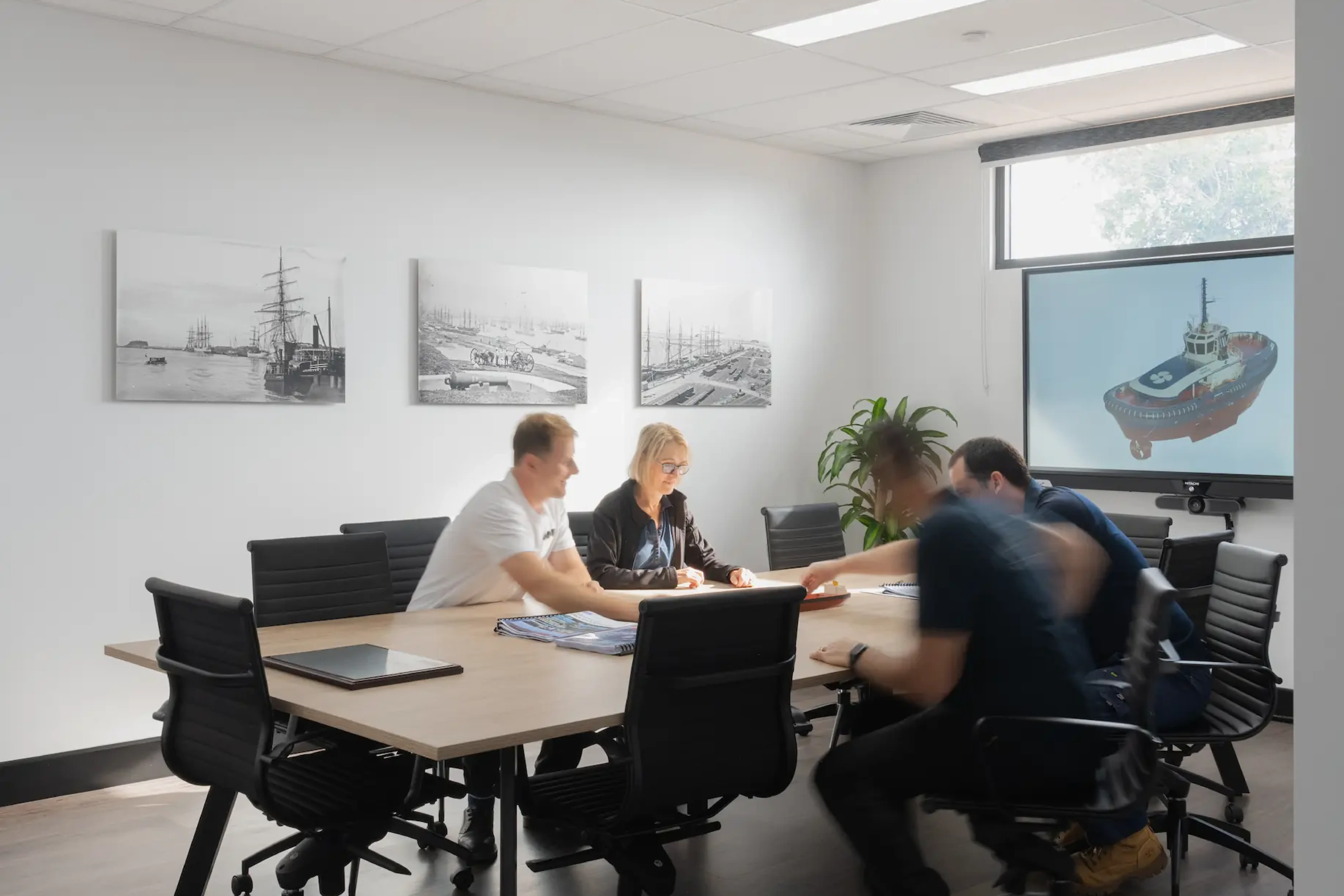 four people sitting around table in board room