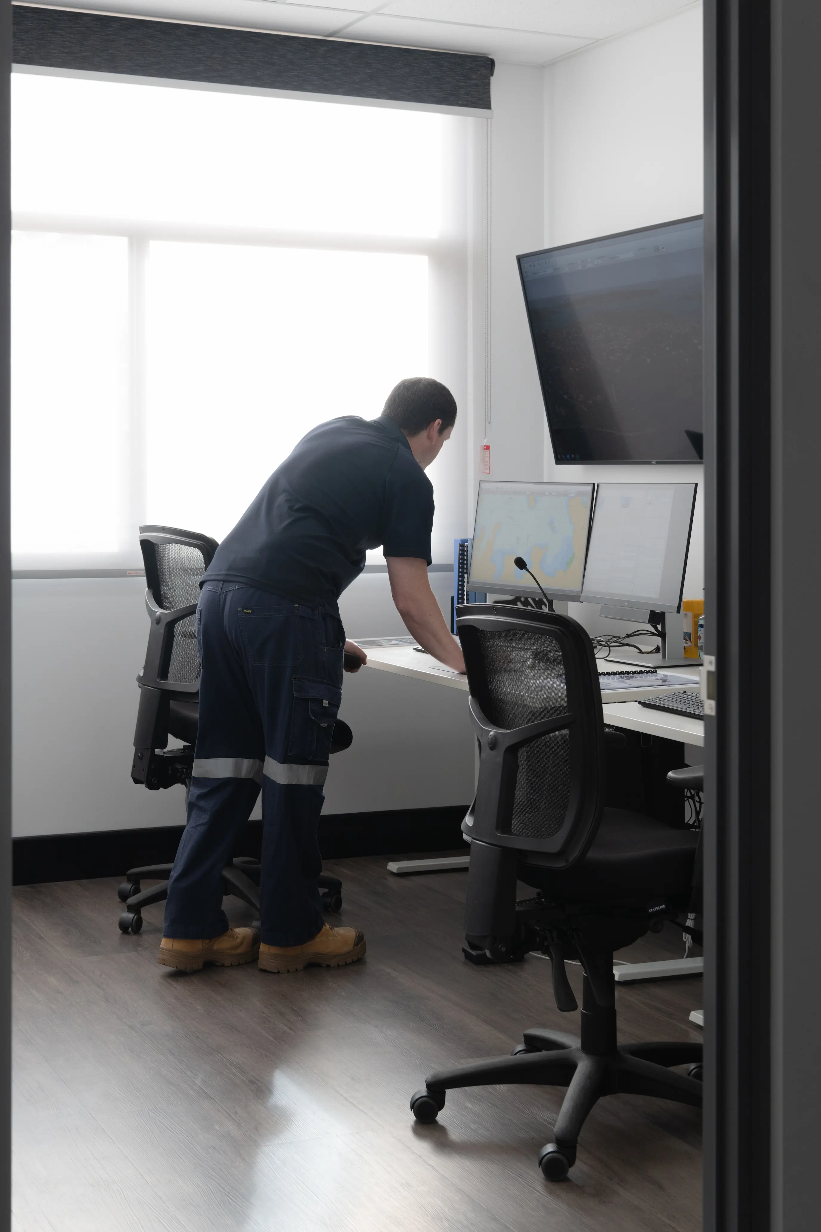 Man in office standing behind computer