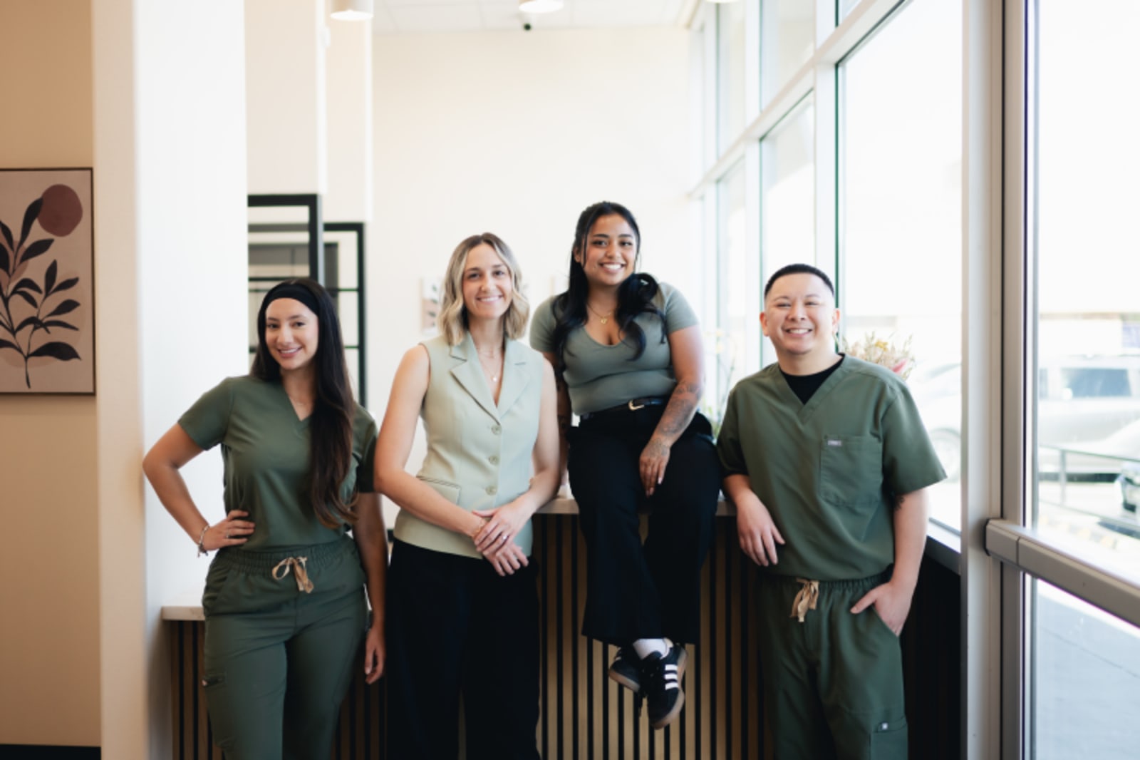 Team of five dental professionals standing together in modern office with windows