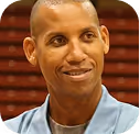 Smiling person in light blue shirt against brick wall background