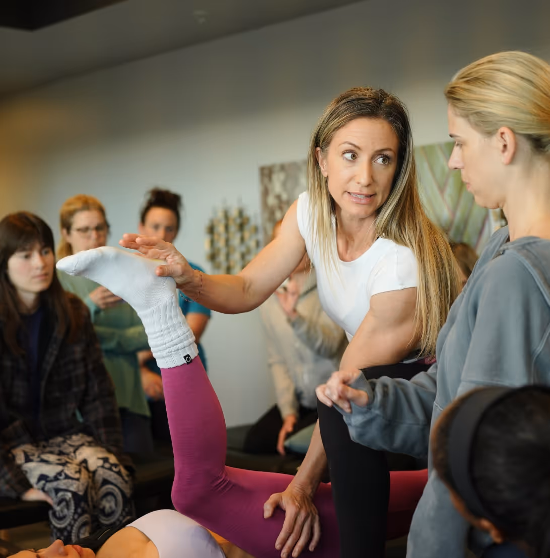 Fitness instructor demonstrating stretching technique to a group in a class