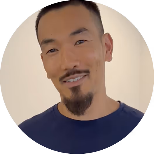 Smiling person in blue shirt, circular portrait with neutral background