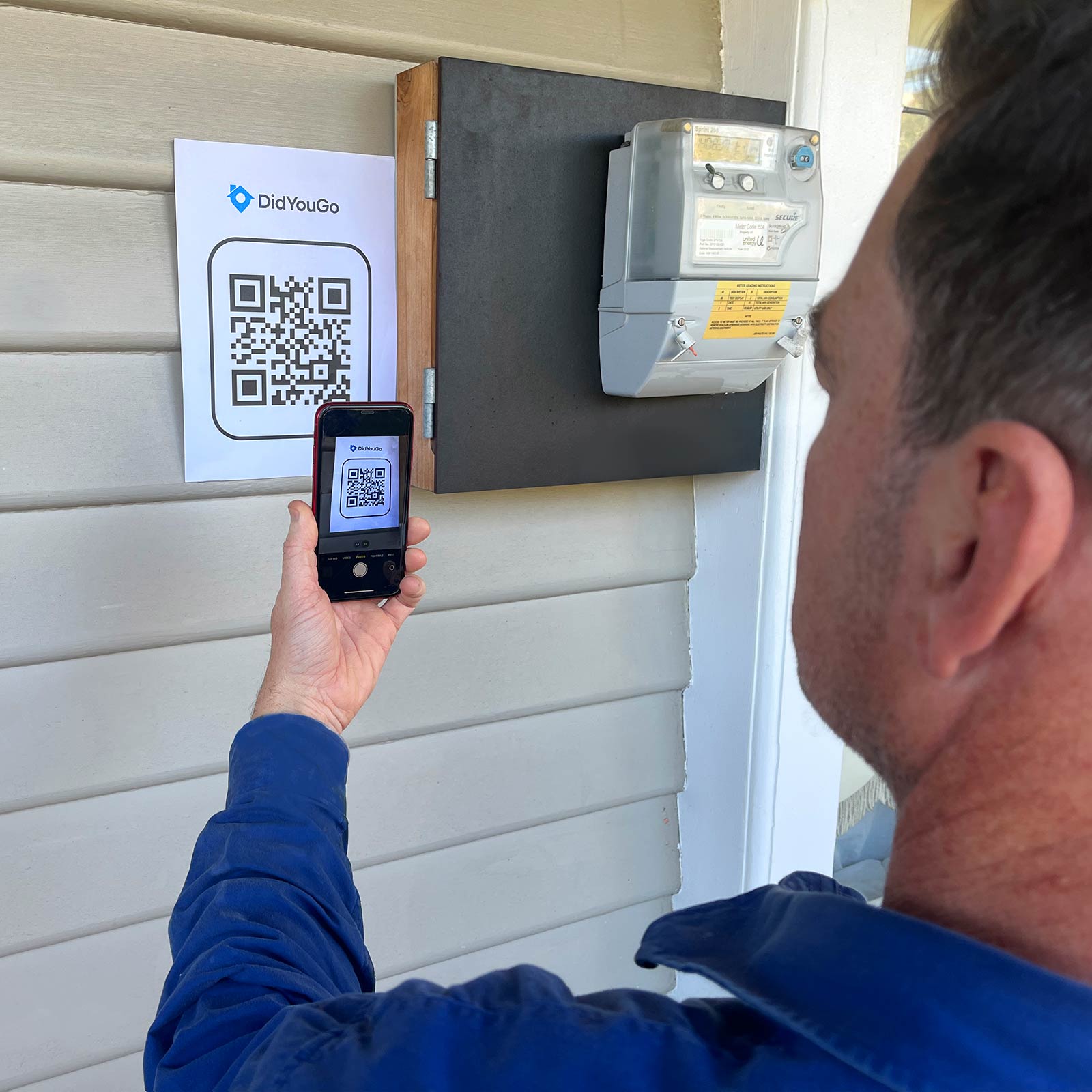 Support worker scanning a DidYouGo QR code near the fuse box at a client's home.