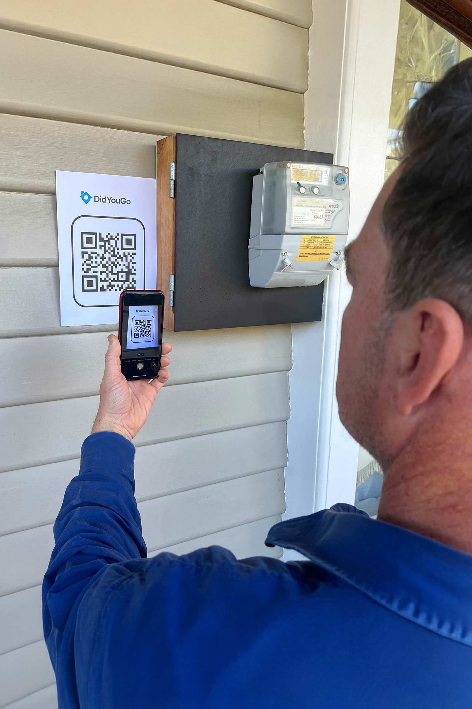 Support worker scanning a DidYouGo QR code near the fuse box at a client's home.