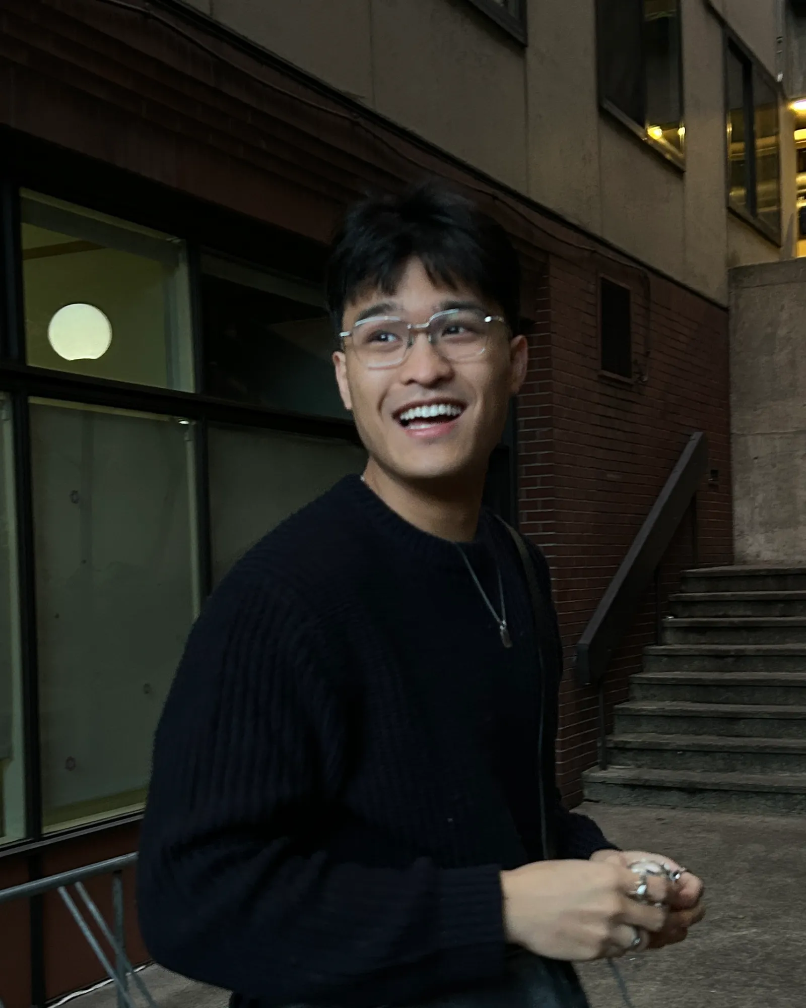 A picture of Samuel Lopez. Black haired Filipino male wearing silver glasses and a blue sweater.