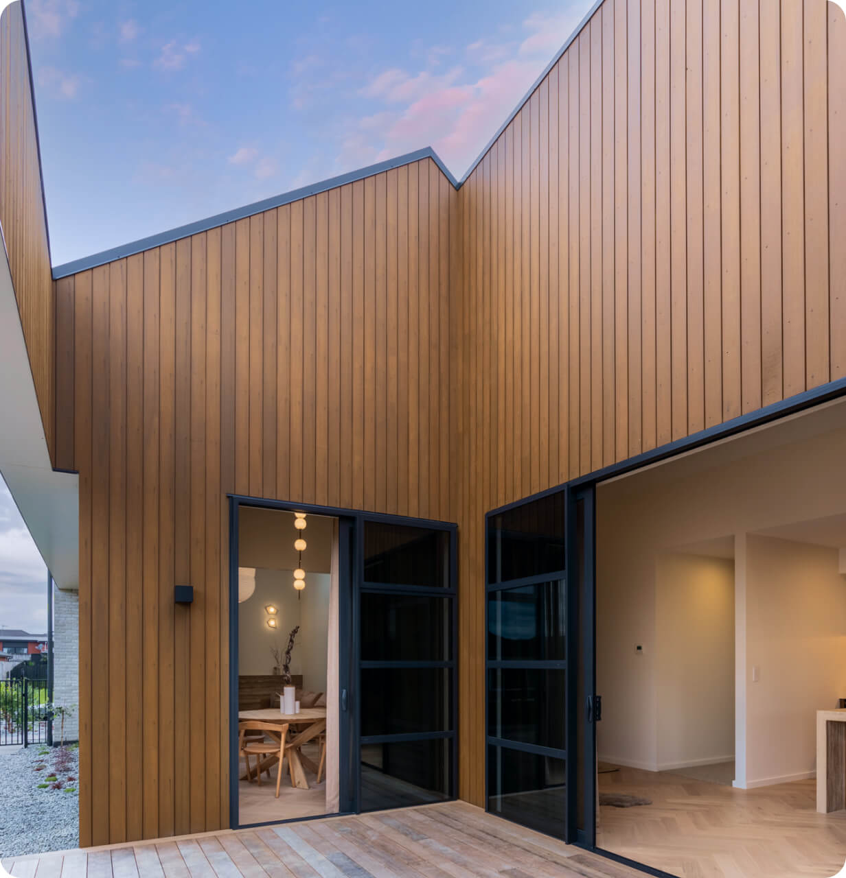 Modern house exterior with vertical wood paneling under a pastel evening sky.