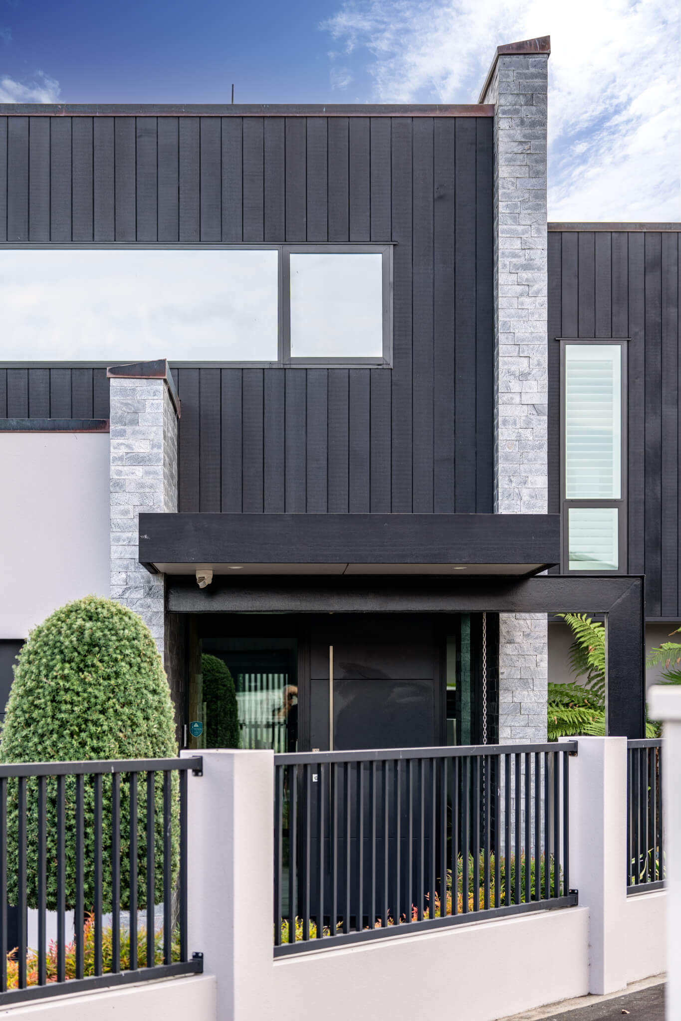 Modern house facade with vertical dark panels and large horizontal window. 