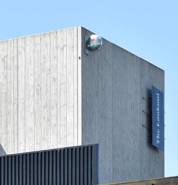 Modern concrete building with vertical lines, a Heineken logo on top, and blue signage reading "The Lookout." 
