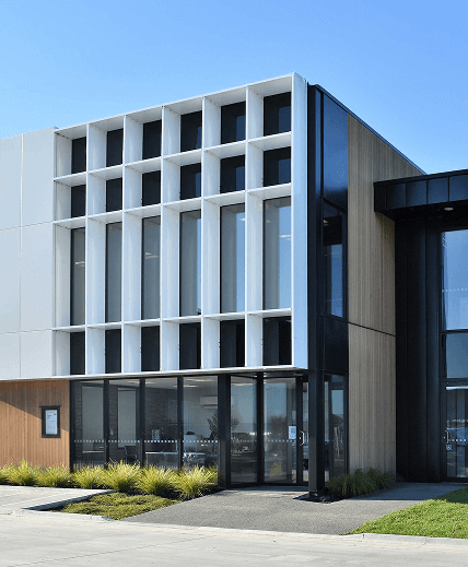 Modern building facade with vertical white panels and glass windows.
