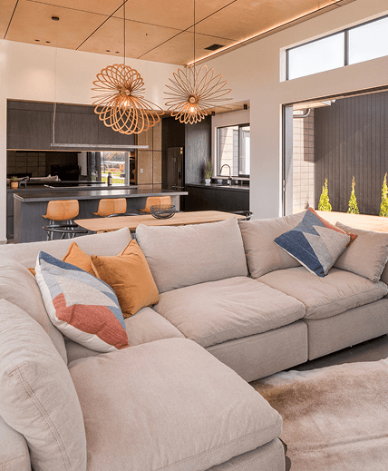 Modern living room with a large beige sectional sofa and colorful pillows.