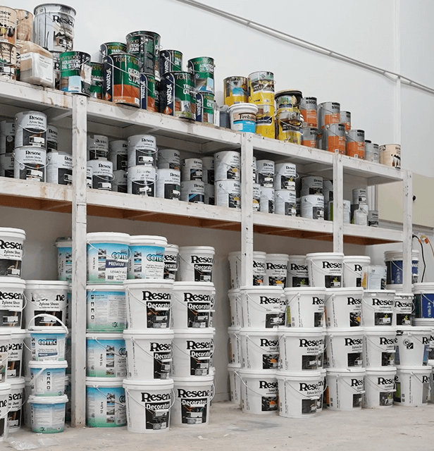 Shelves filled with paint buckets and cans in various colors and brands.