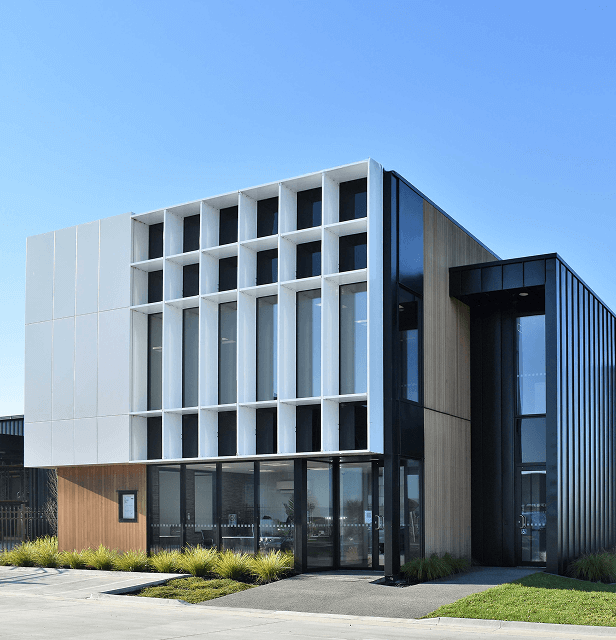 Modern building facade with vertical white panels and glass windows.