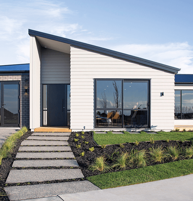 Modern house with angular roof, large windows, and light gray siding. 