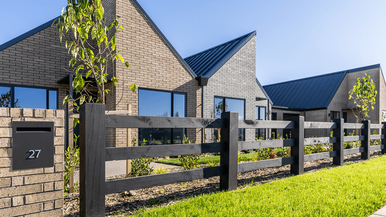 Modern townhouses with pitched roofs and brick exteriors under a clear blue sky. 