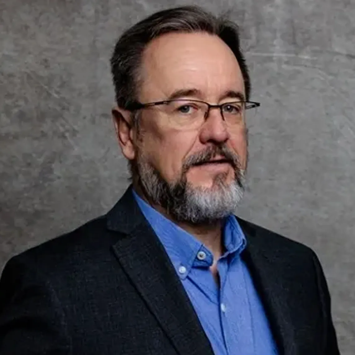 Portrait of Critical Tilt’s director in suit with glasses