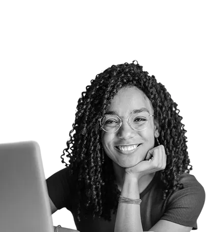 Smiling woman with curly hair working on laptop, grayscale background
