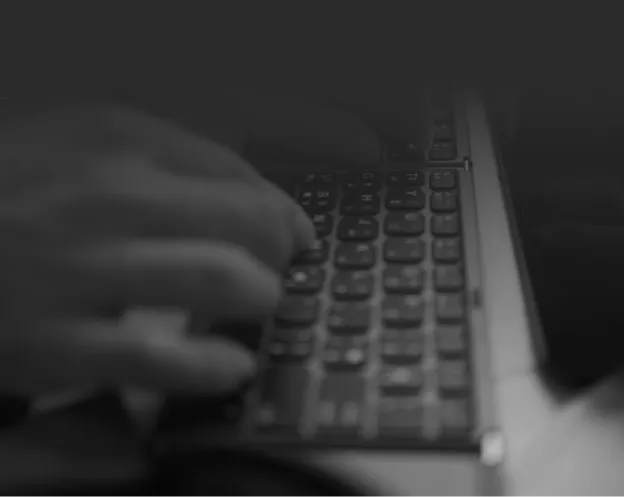 Hands typing on a laptop in a dark environment
