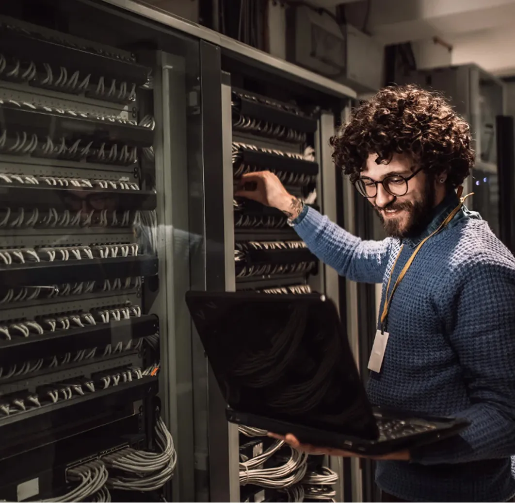 Engineer managing server room with confident smile