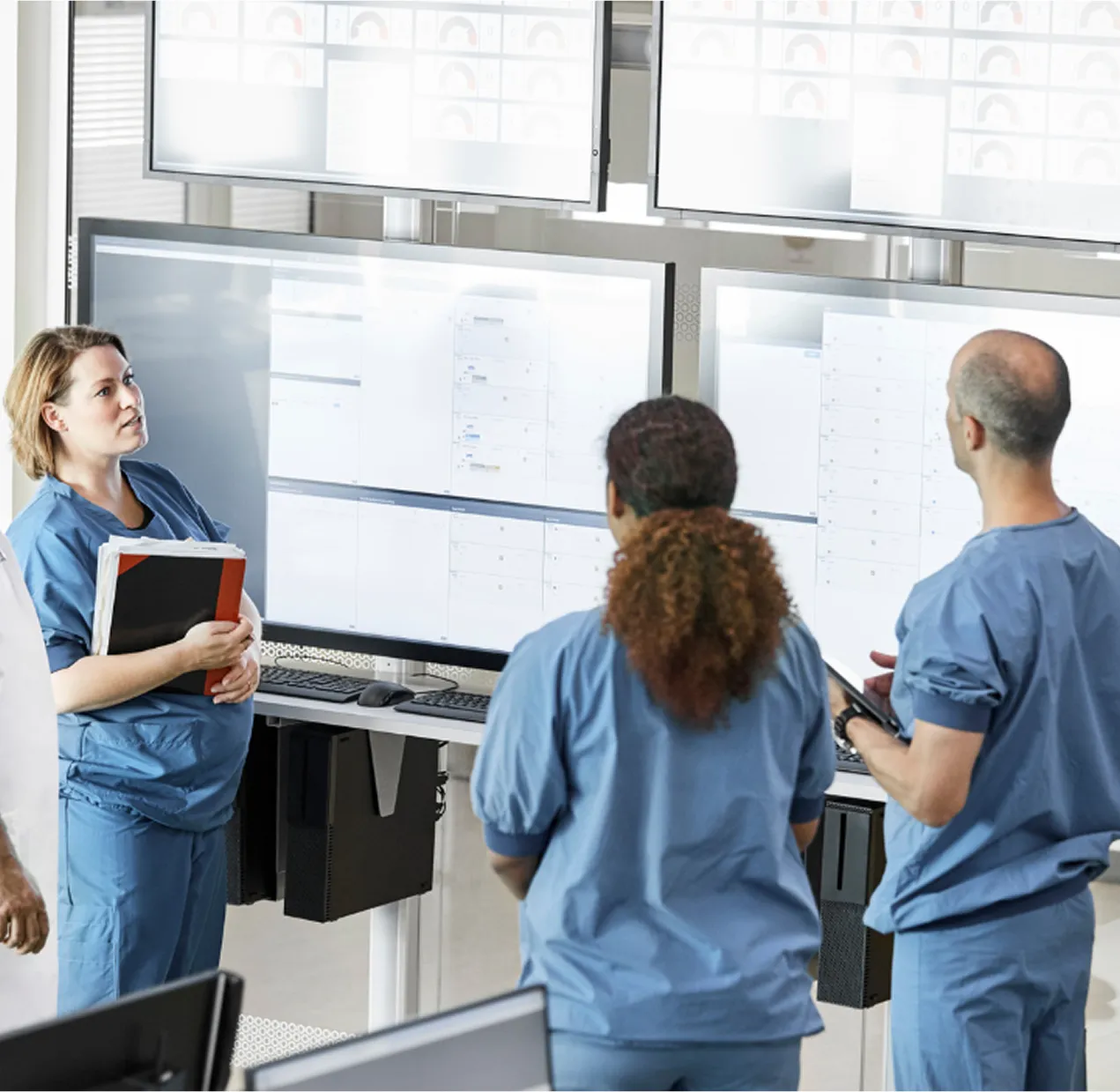 Medical professionals analyzing data on large screens in a hospital