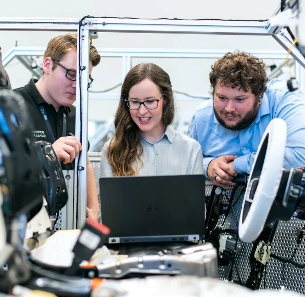 Engineers troubleshooting manufacturing equipment with a laptop