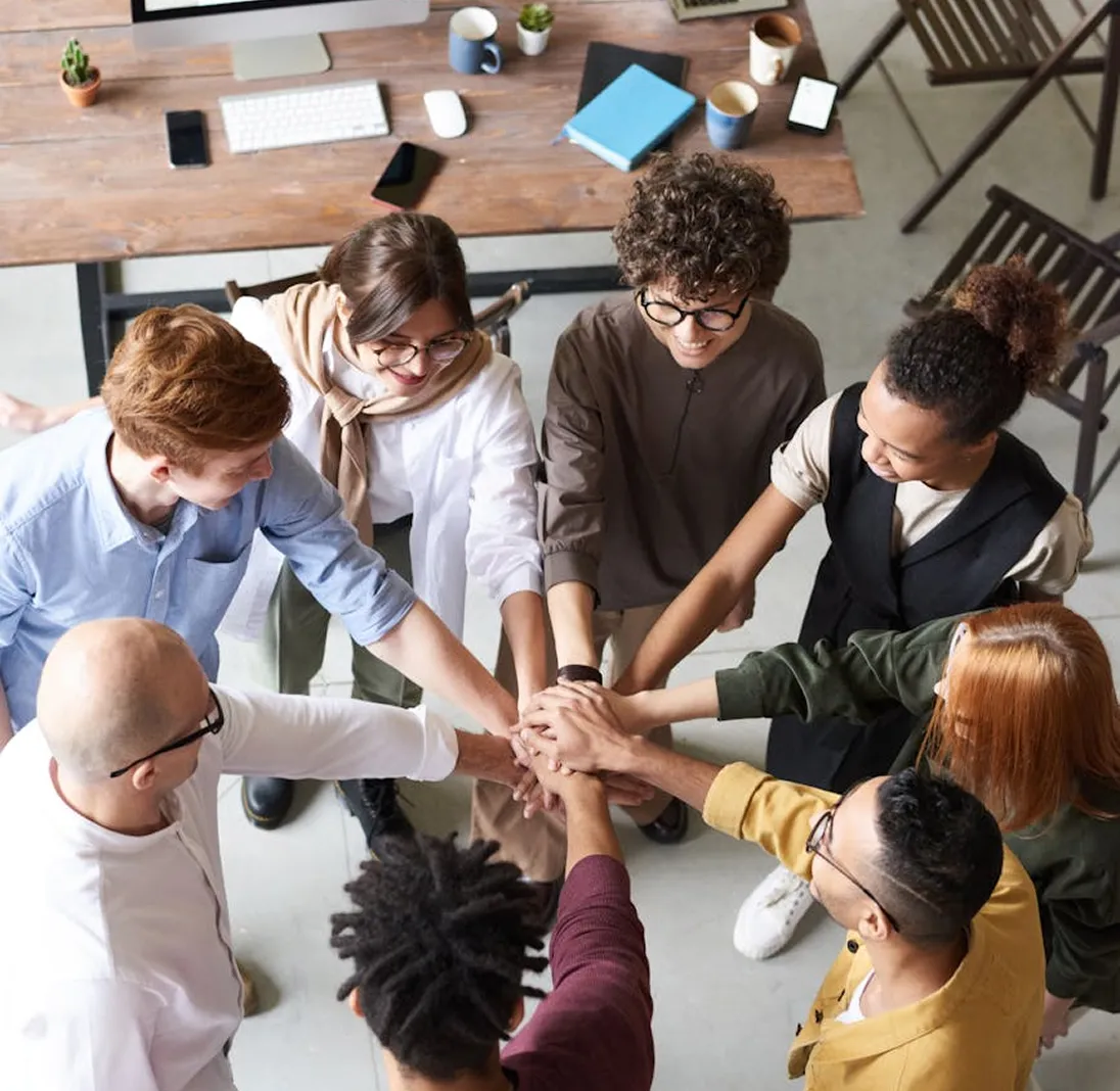 Diverse team stacking hands in a collaborative workspace
