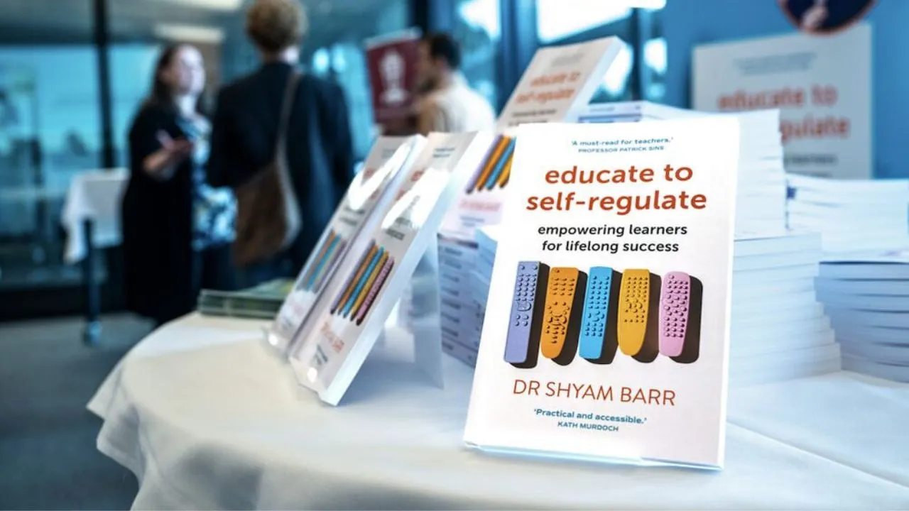 Books titled 'educate to self-regulate' by Dr. Shyam Barr displayed on a table in a public space.