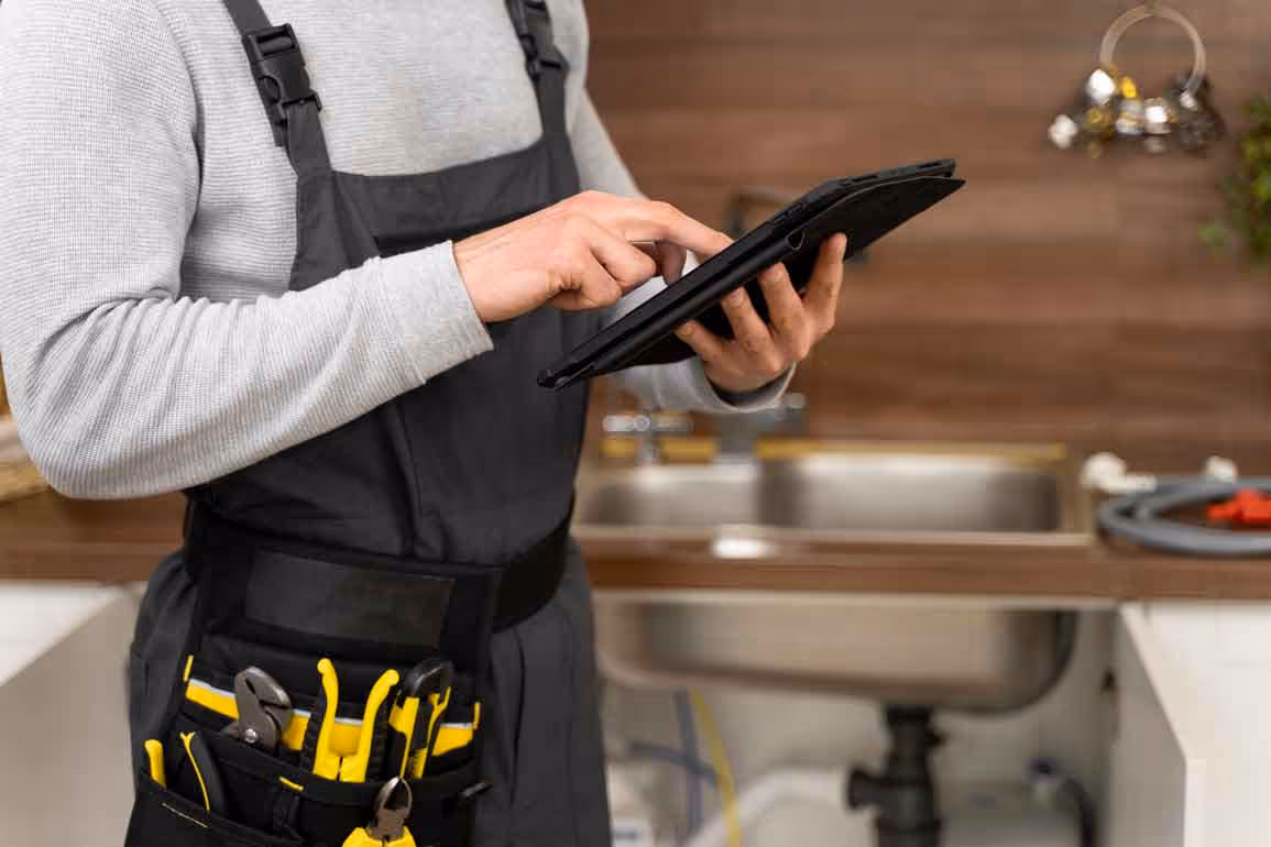 Sunshine Services technician checking service details on a tablet during a plumbing inspection in Florida