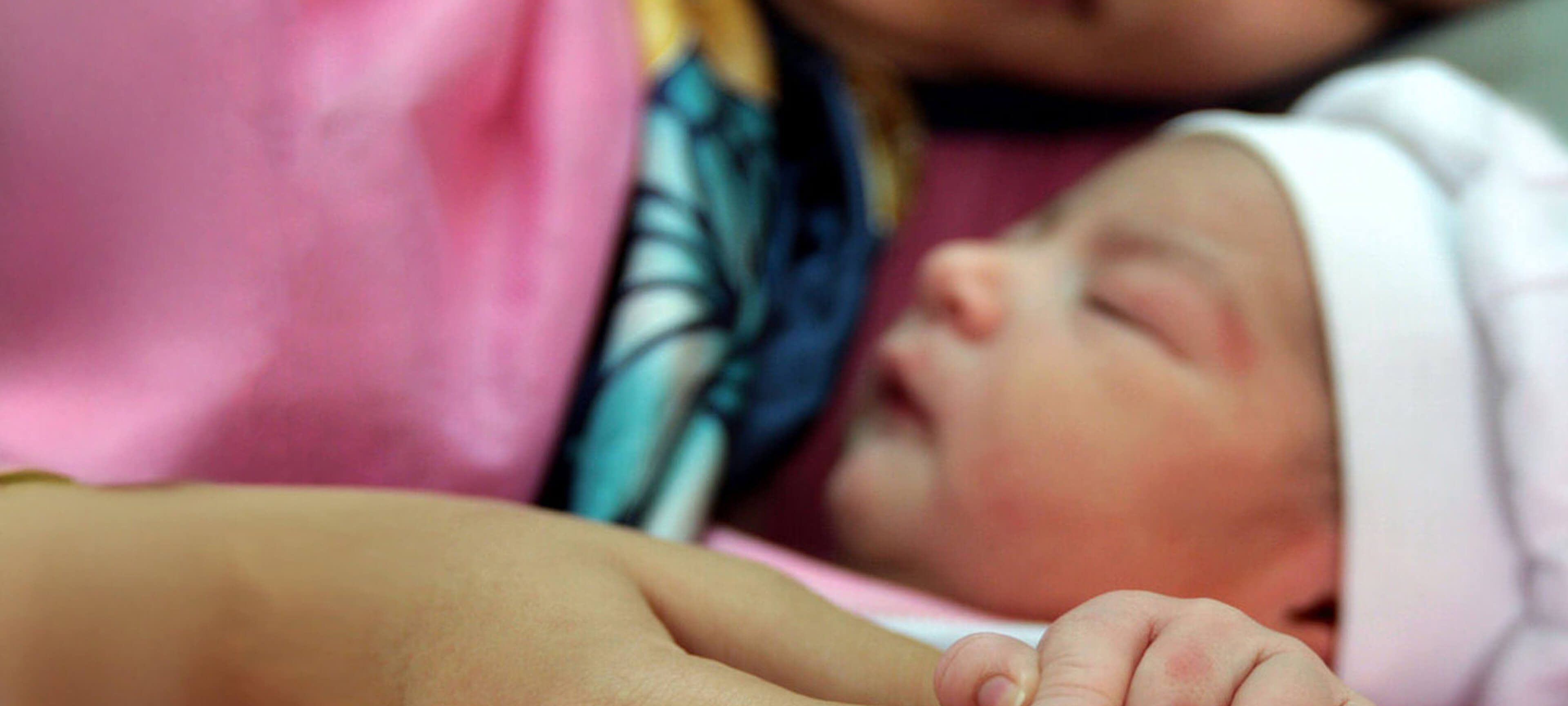 Newborn baby sleeping peacefully in a caregiver’s arms