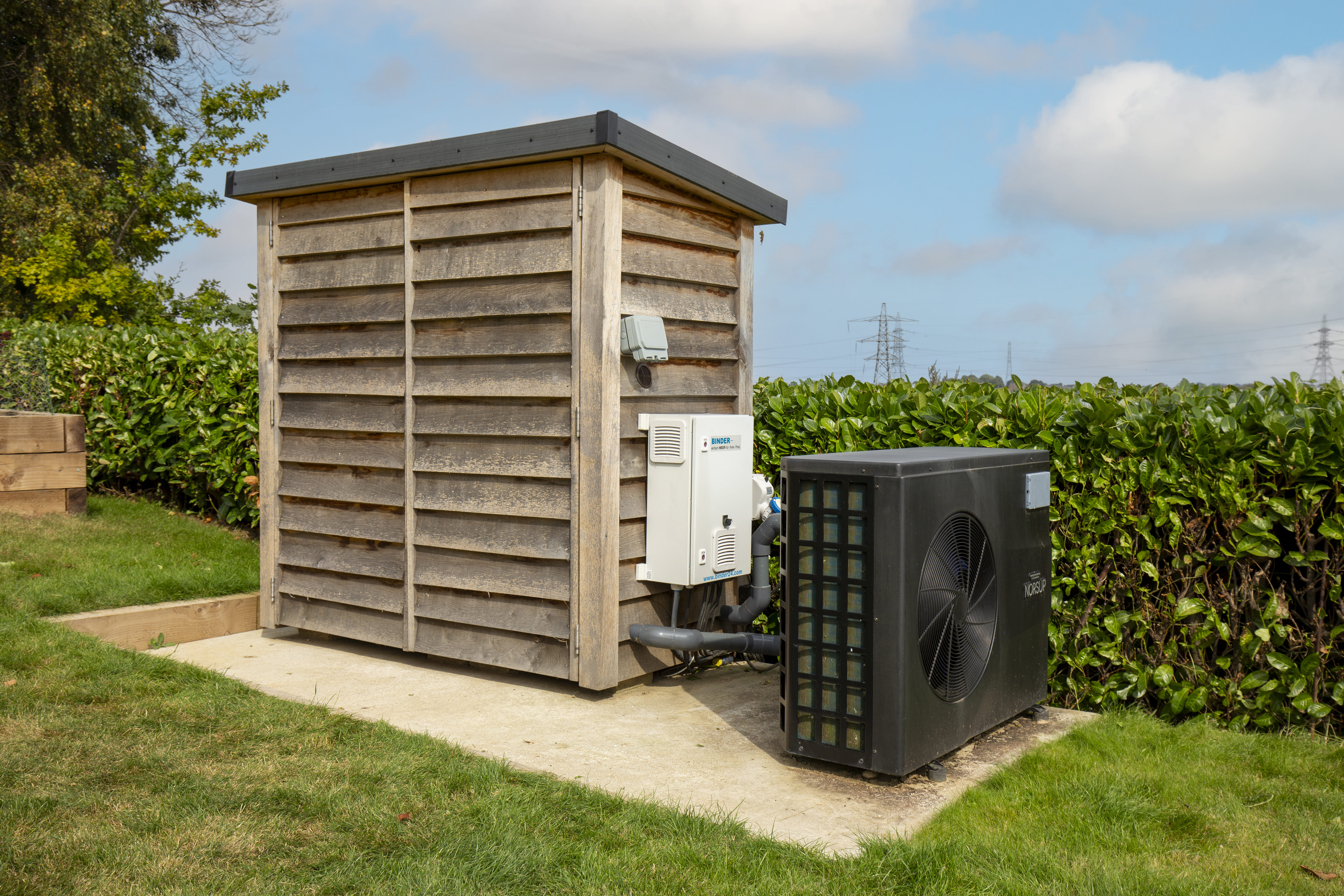 a pool heat pump next to an oak pool plant room structure