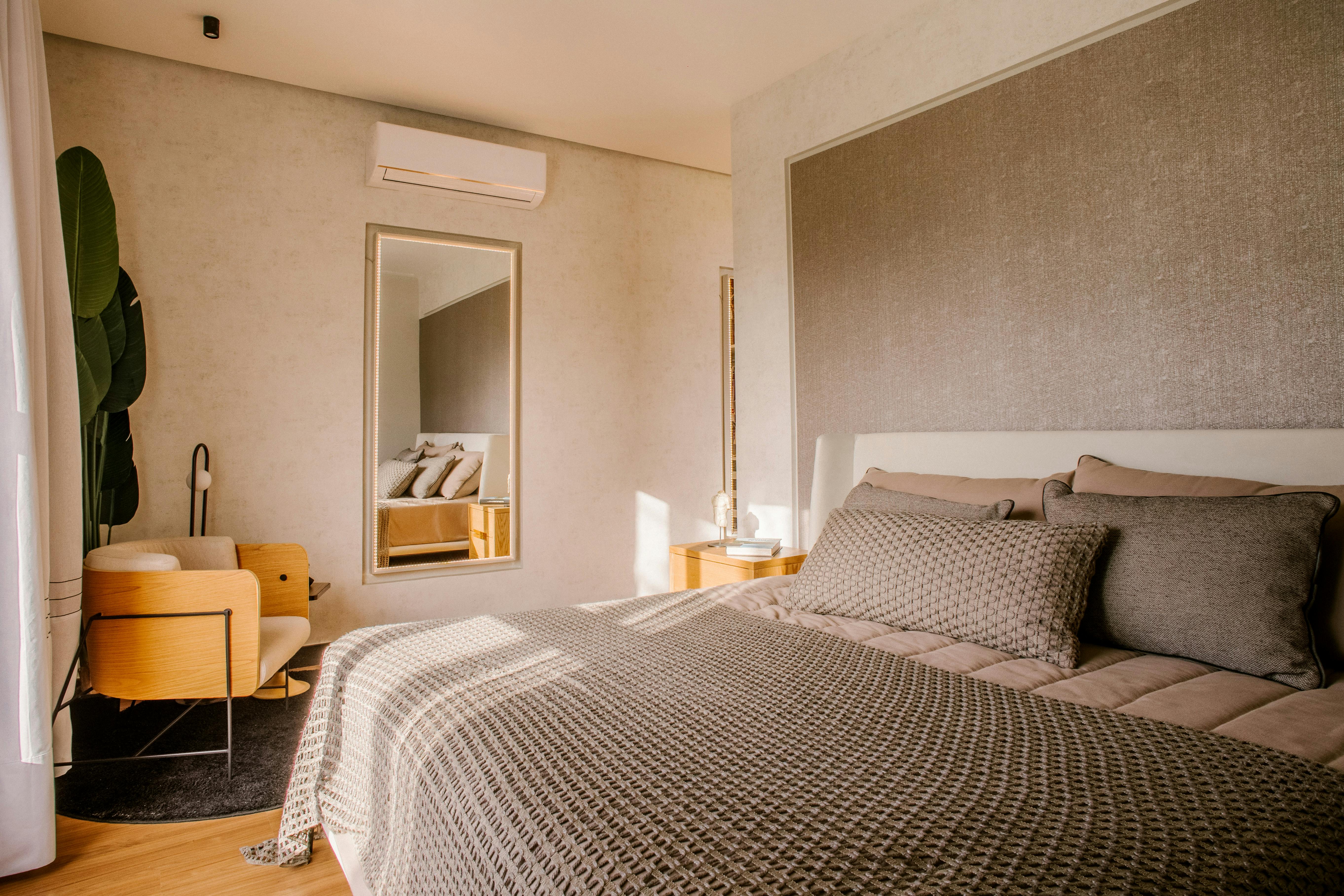 a boho inspired bedroom with an air con unit on the back wall above a mirror