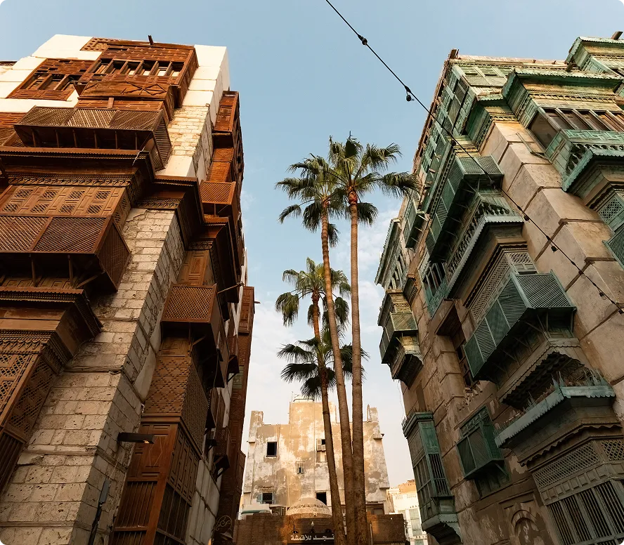 Two businessmen, one in traditional Middle Eastern attire and the other in a blue suit, looking at a tablet together.