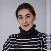 Portrait of Carla Lima of Promiris, wearing a black-and-white striped turtleneck sweater