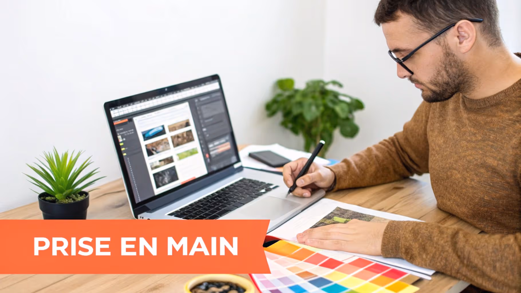 Une personne assise à un bureau, esquissant un design de site web sur une tablette graphique, avec un ordinateur portable ouvert à côté.