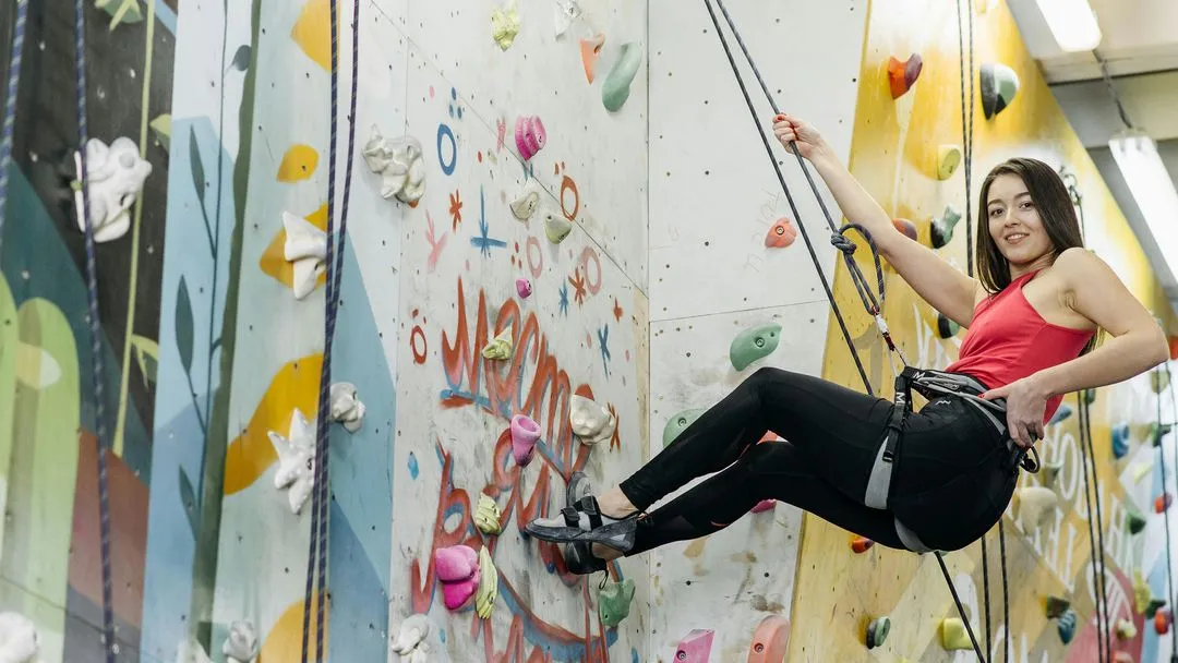 Climber hanging on to rope on graffiti rock wall 