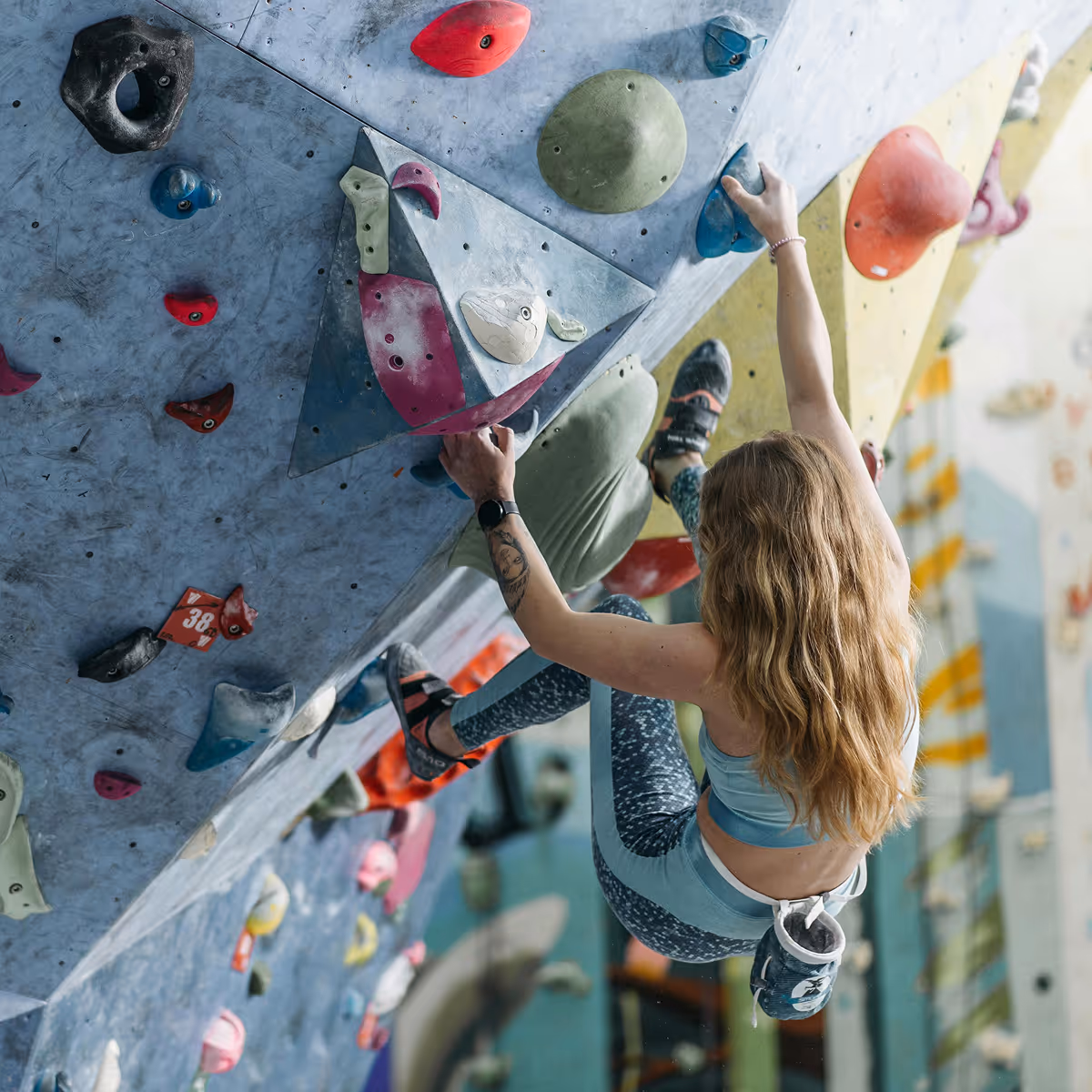 Climber hanging from blue rock wall