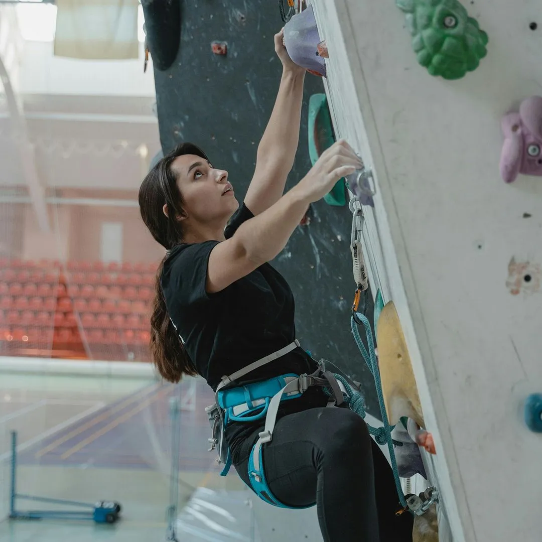Young climber climbing up belay wall