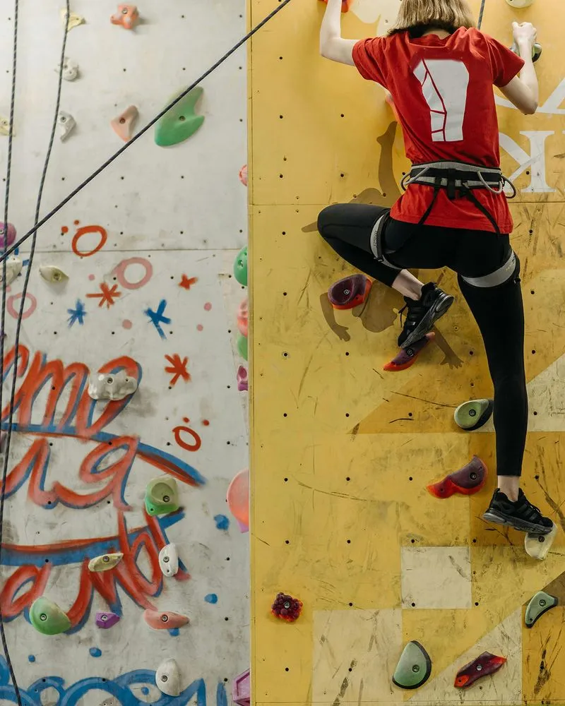 Rock climber in red shirt climbing yellow wall