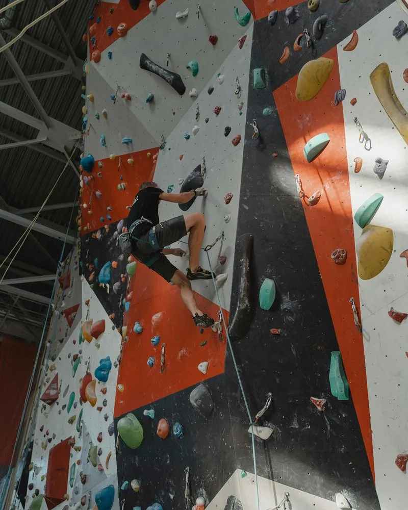 Rock climber going up white, red, and black wall