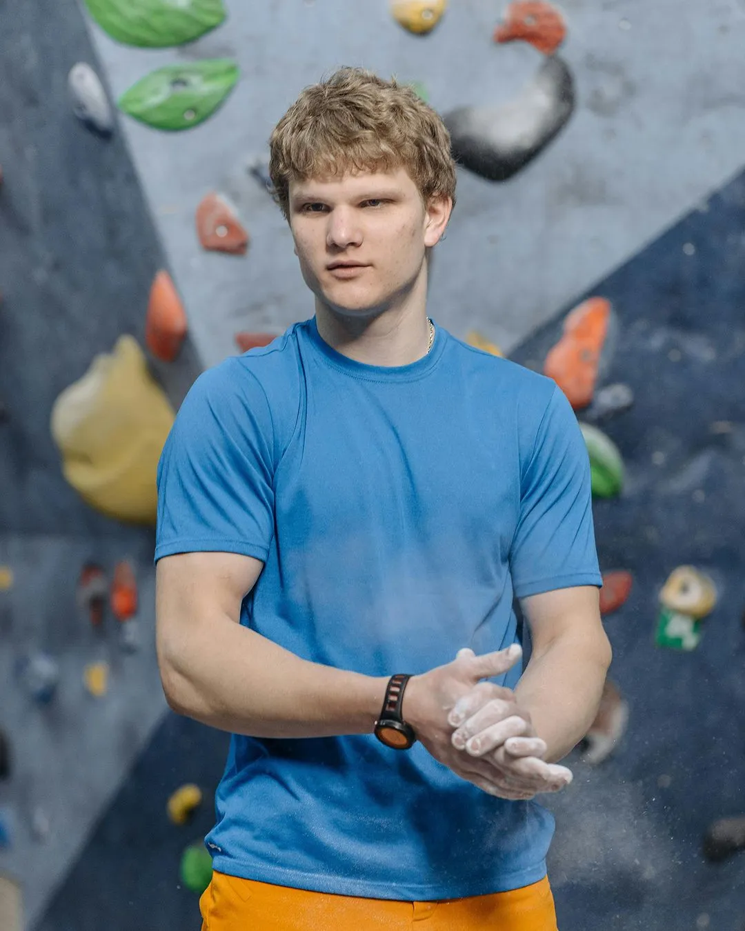 Rock climber wearing blue shirt and orange shorts