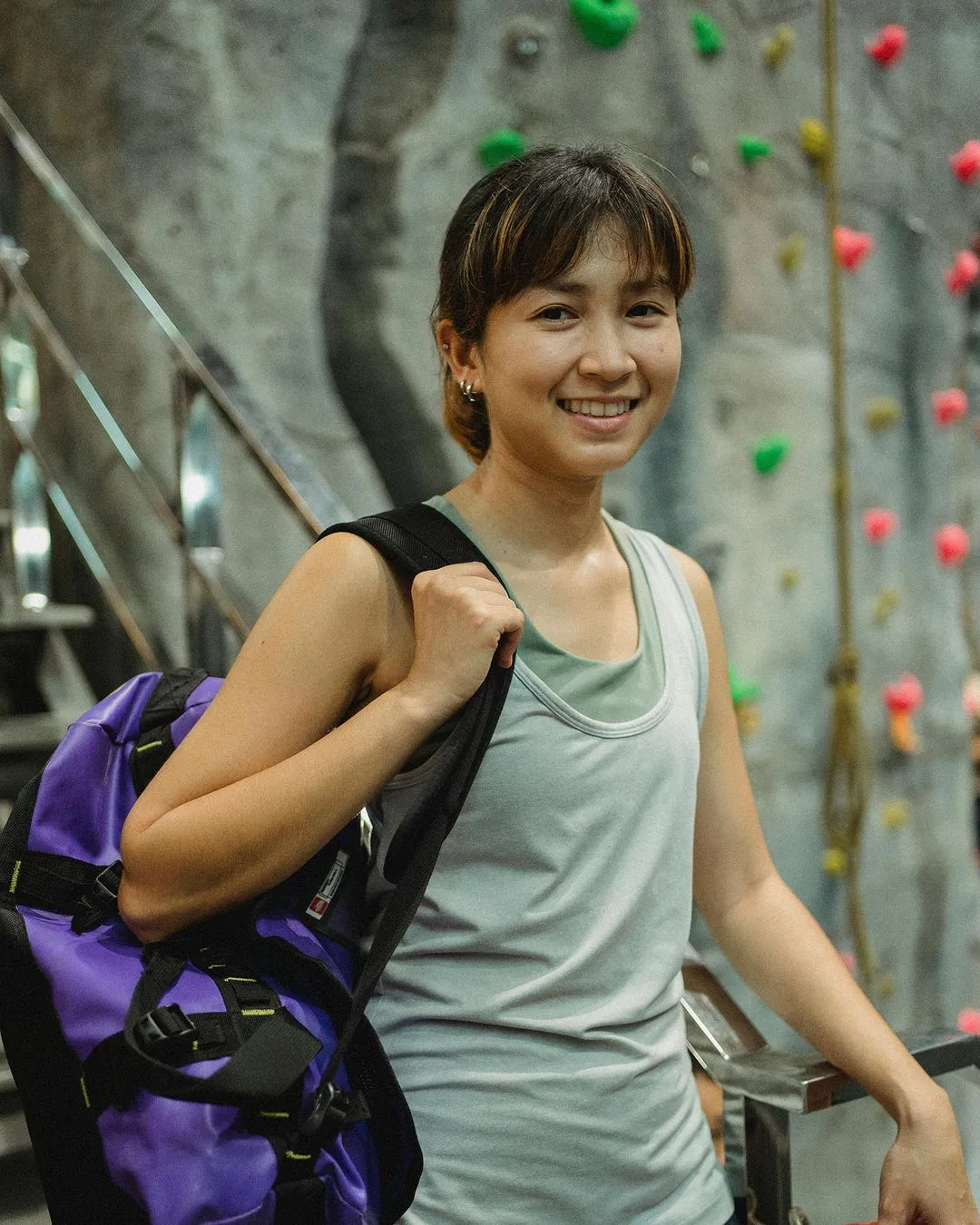 Rock climber holding with grey tank and purple bag